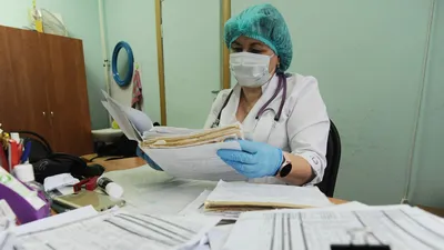 Фото Стоя в офисе улыбается женщина-врач, холдинг папка